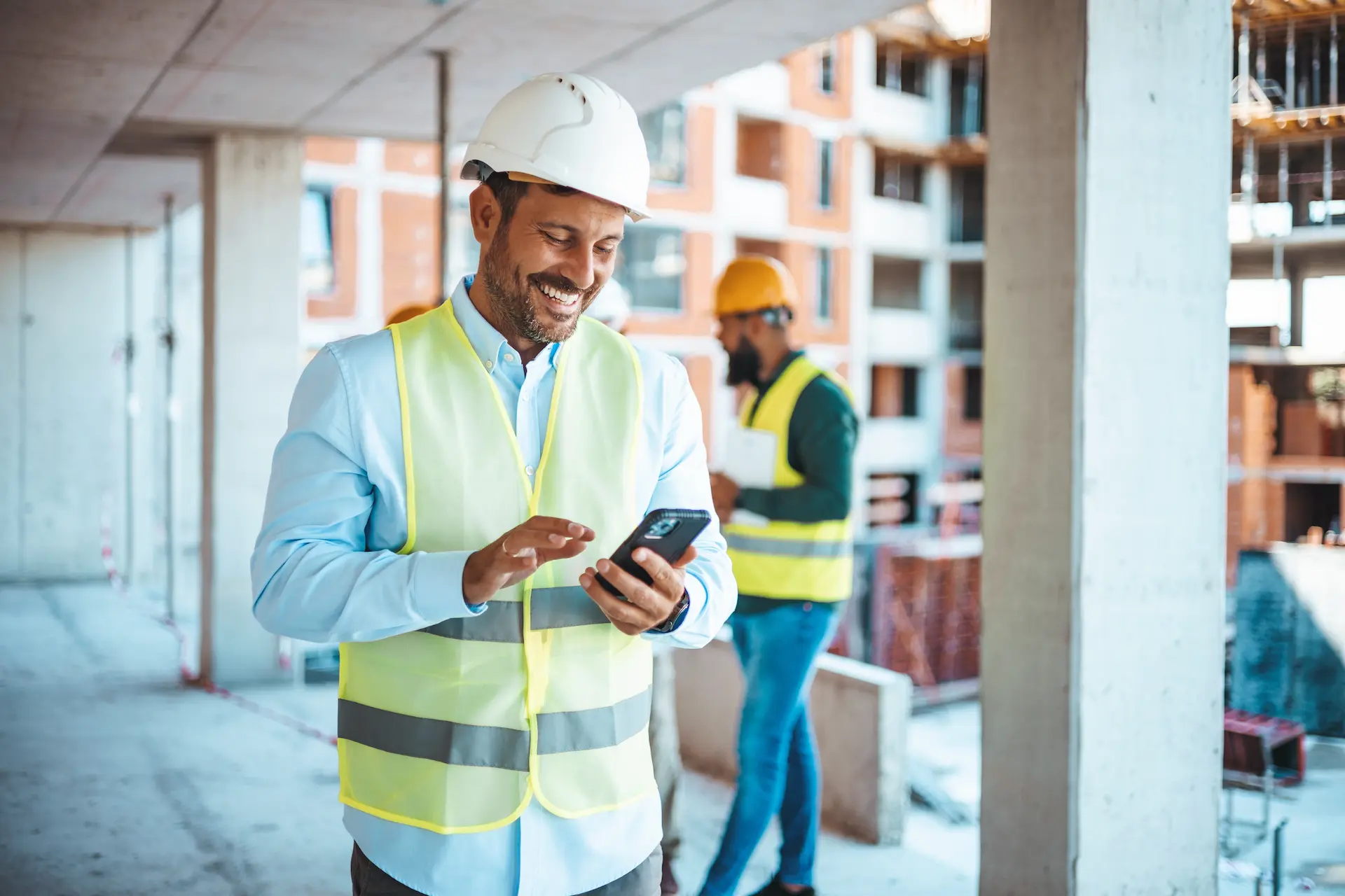 Young Construction Worker Smiling at Phone, Applying for Machinery Loan
