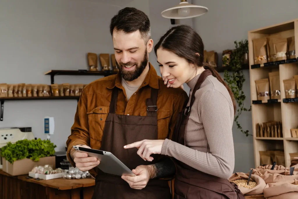 man and woman smiling and using tablet computer in local eco shop